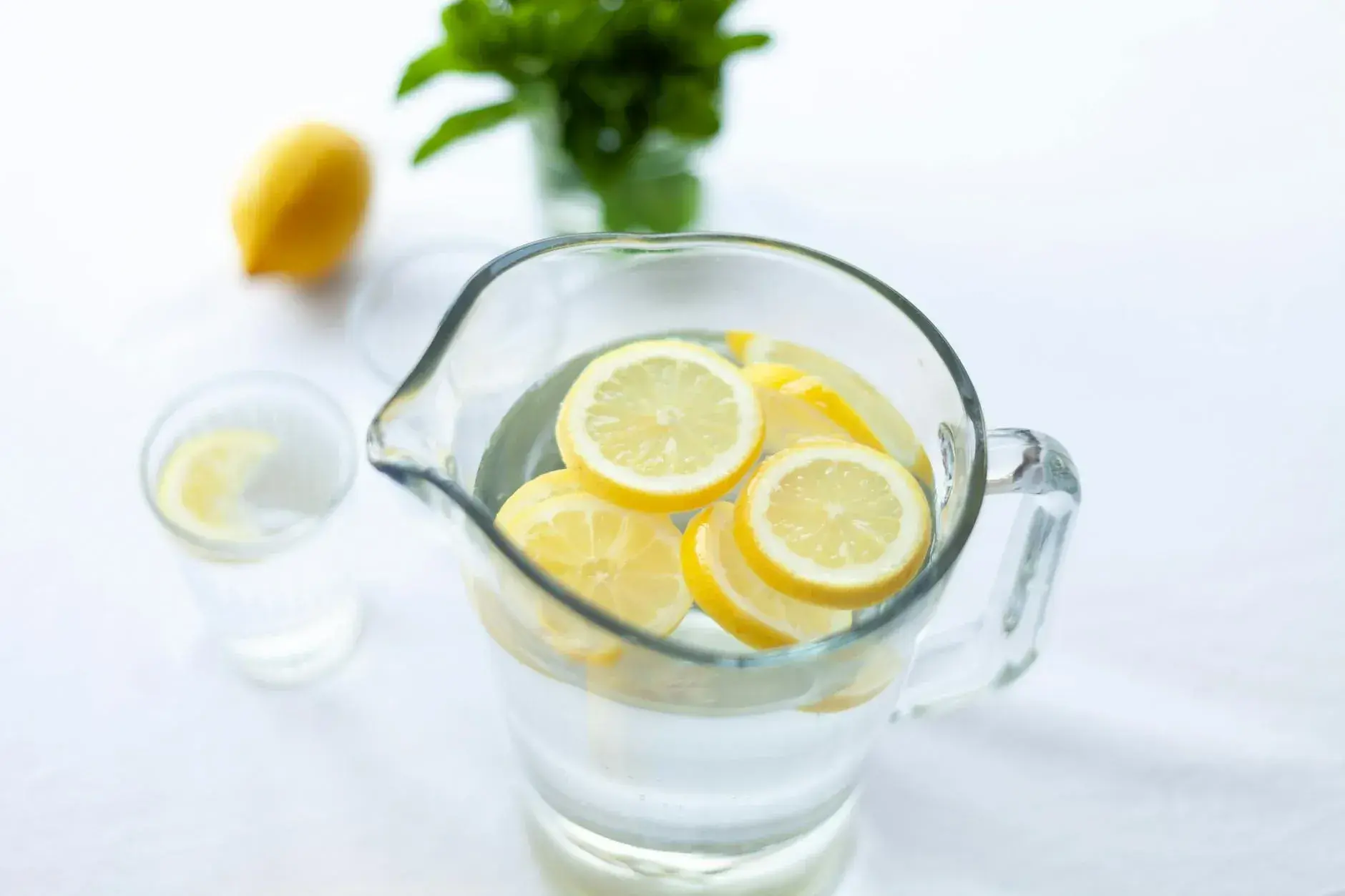 En forfriskende kande vand fyldt med friske citronskiver set fra oven, ideel som tørstslukker.