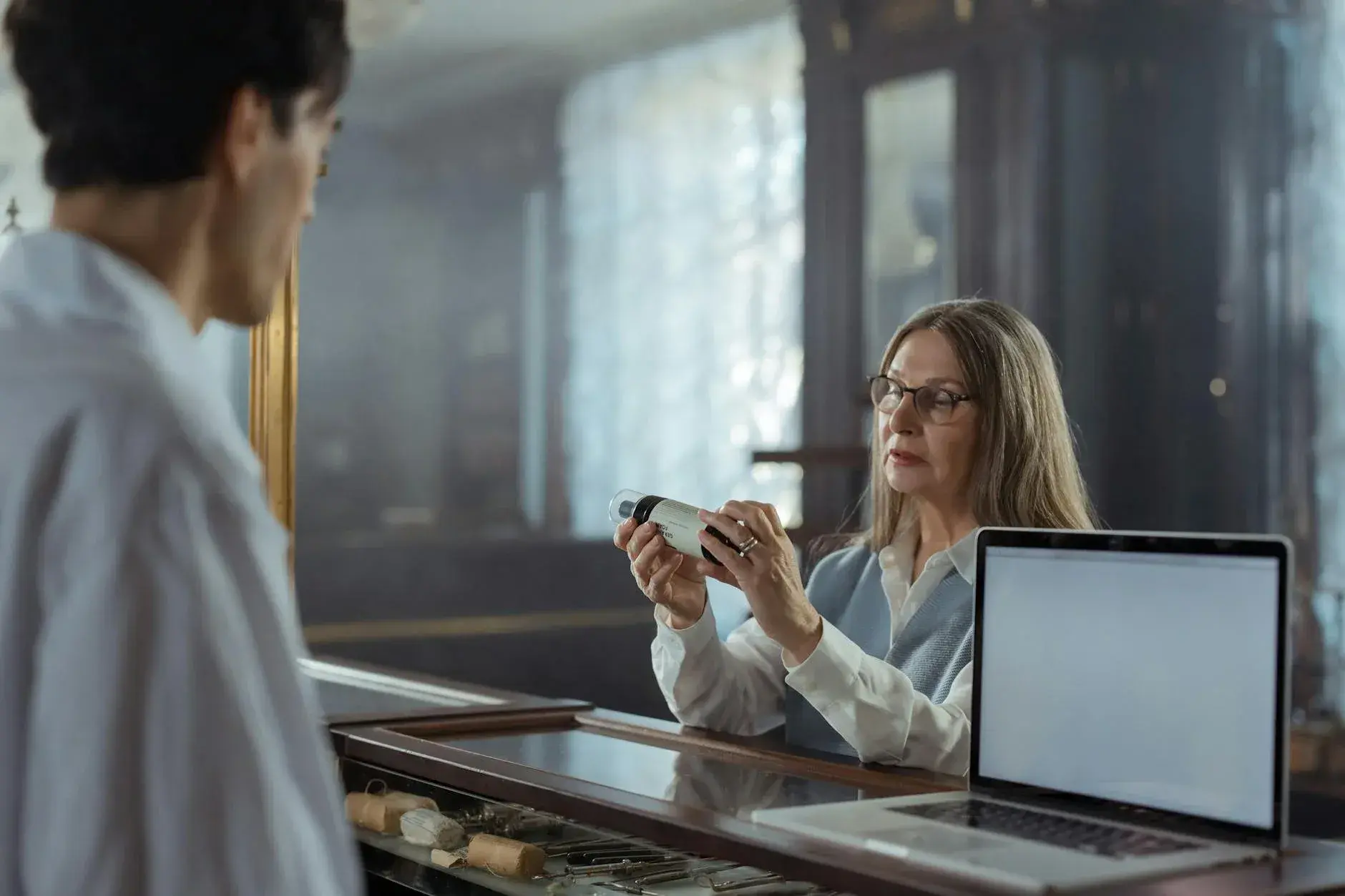 En farmaceut i dialog med en kunde om korrekt brug af medicin ved en apoteksskranke.