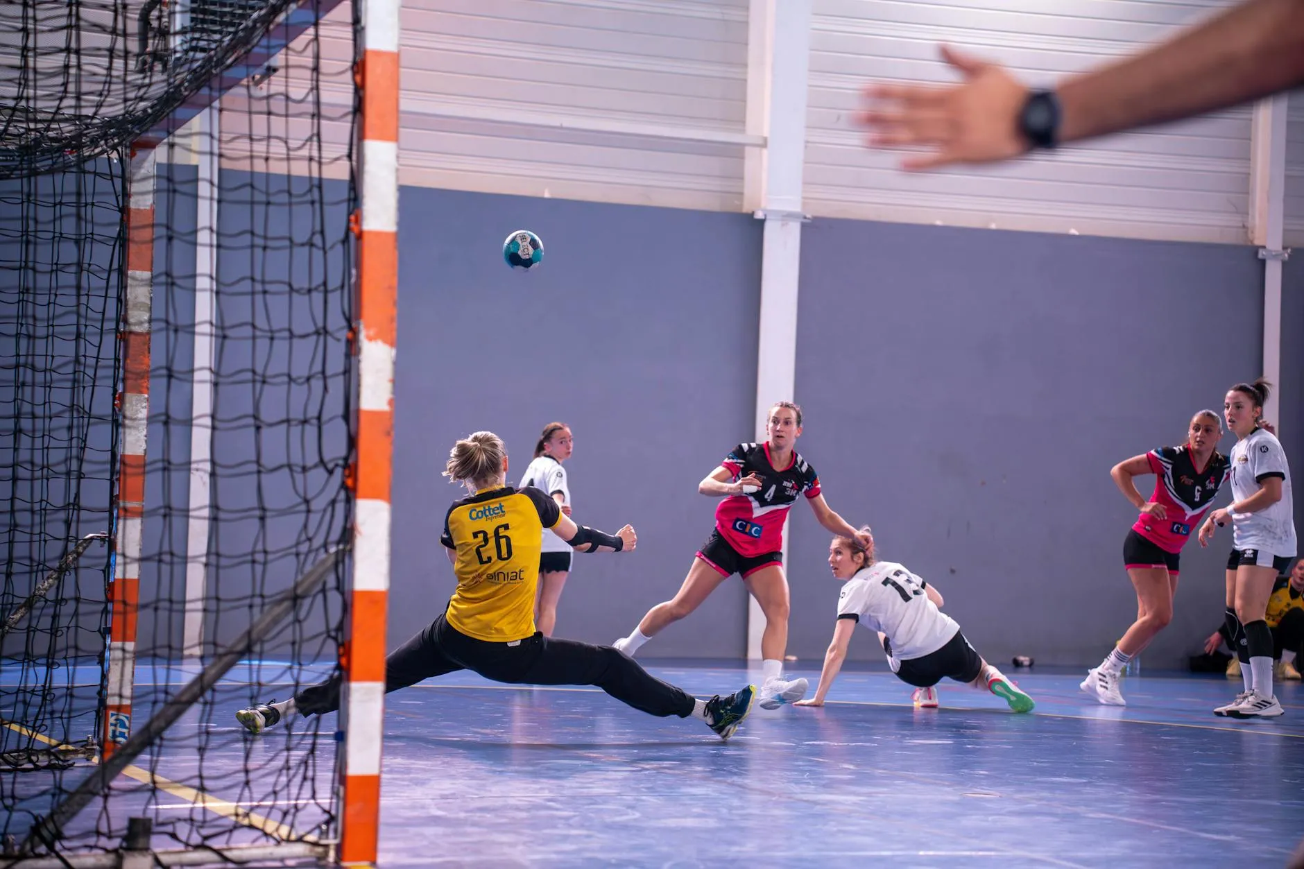En dynamisk aksjonsbillede af kvinder i en håndboldkamp, med spillere i midt-fase.