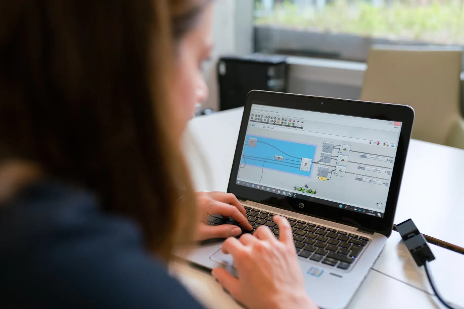 En kvinde i en indendørs setting, der fokuserer på softwareanalyse ved hjælp af en laptop. Hun er en del af en moderne teknologi-verden.