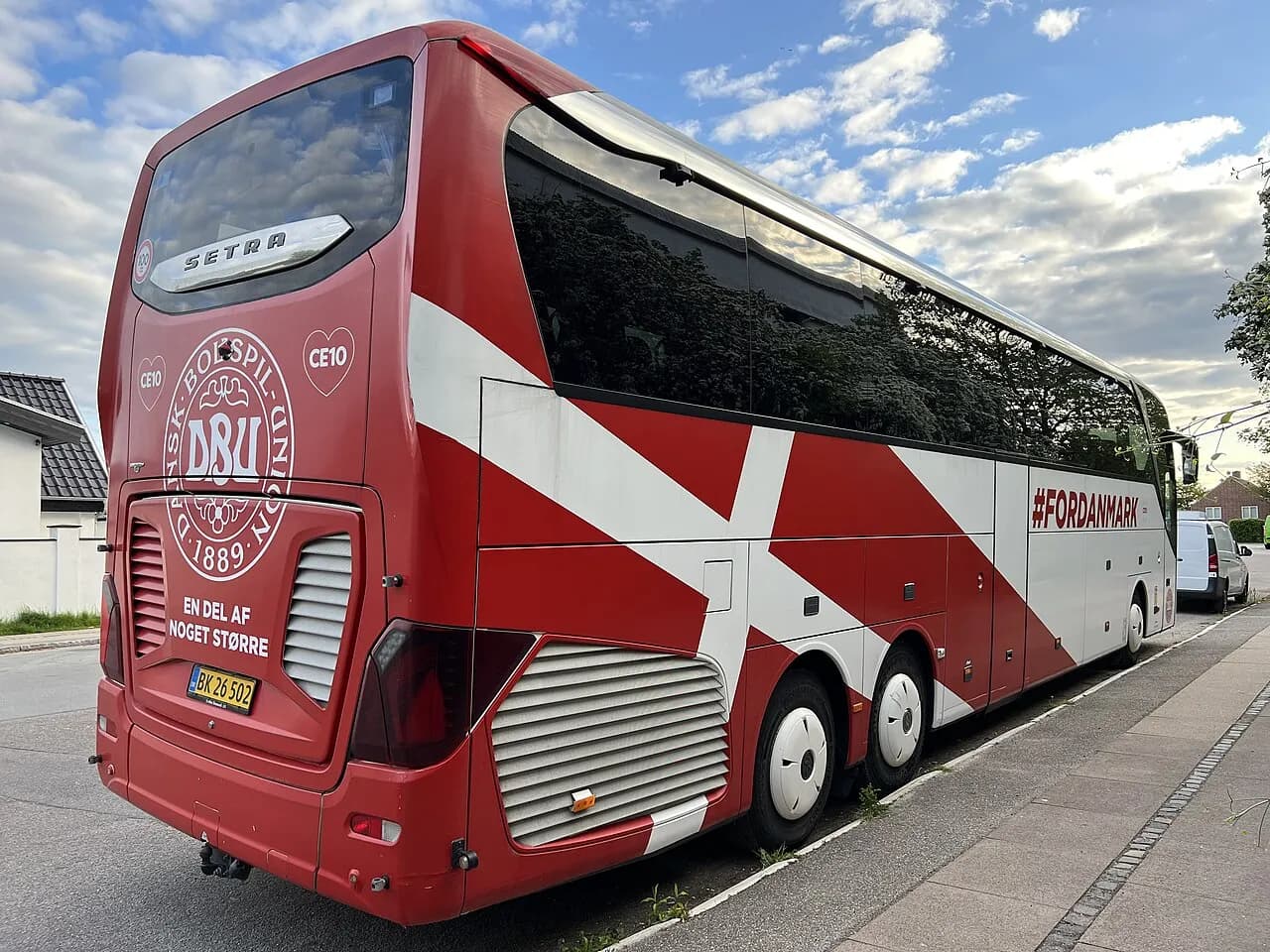 A white Setra bus with the Danish Football Association logo and flag, parked near residential areas in Copenhagen.
