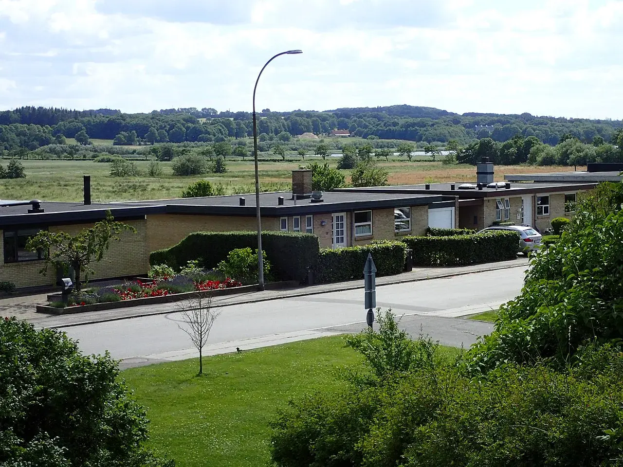 A scenic view of Hougårdsvej road stretching across the tranquil Brabrandsøen lake.