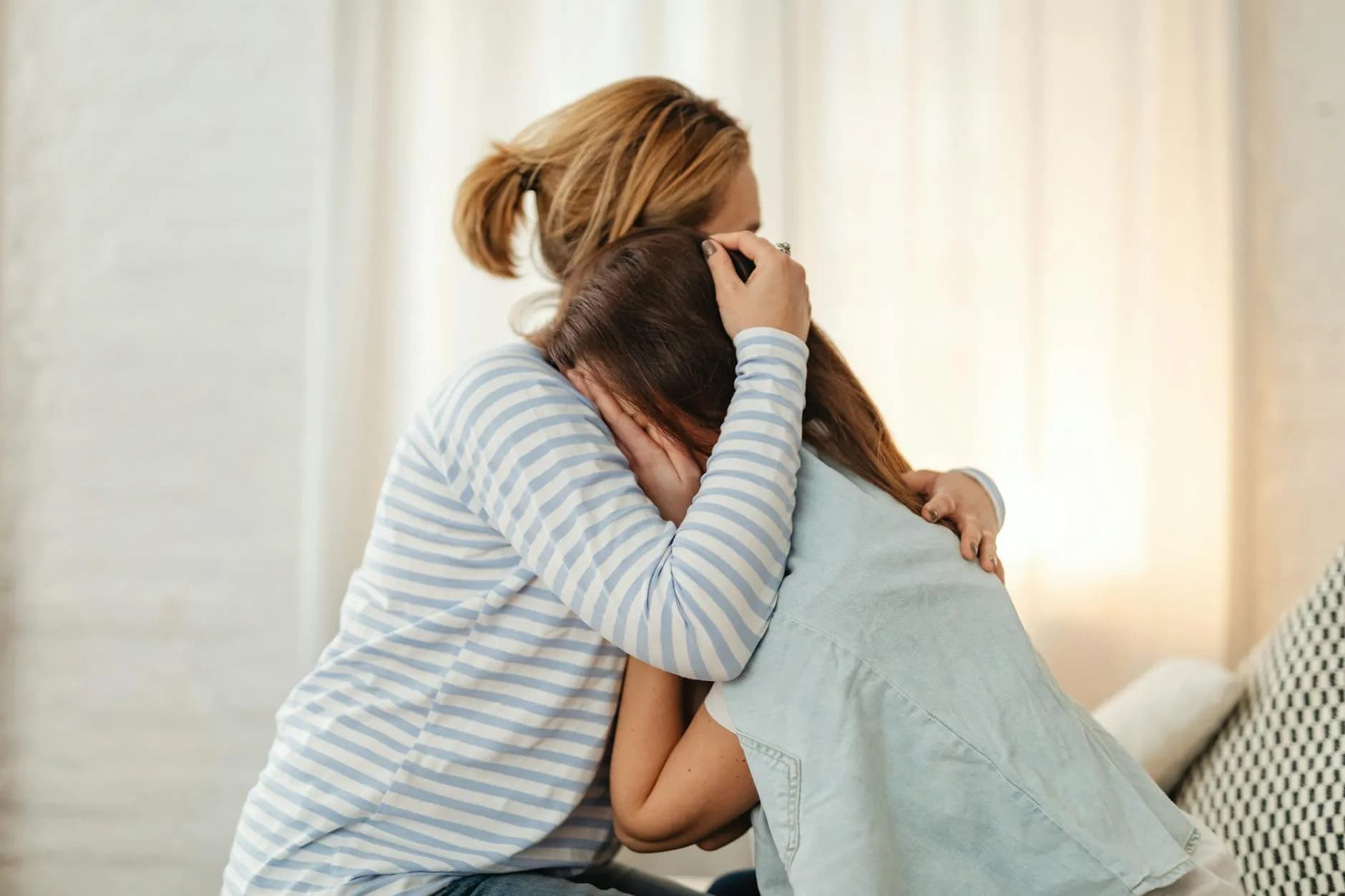 A mother provides comforting support to her teenage daughter in a heartfelt embrace.