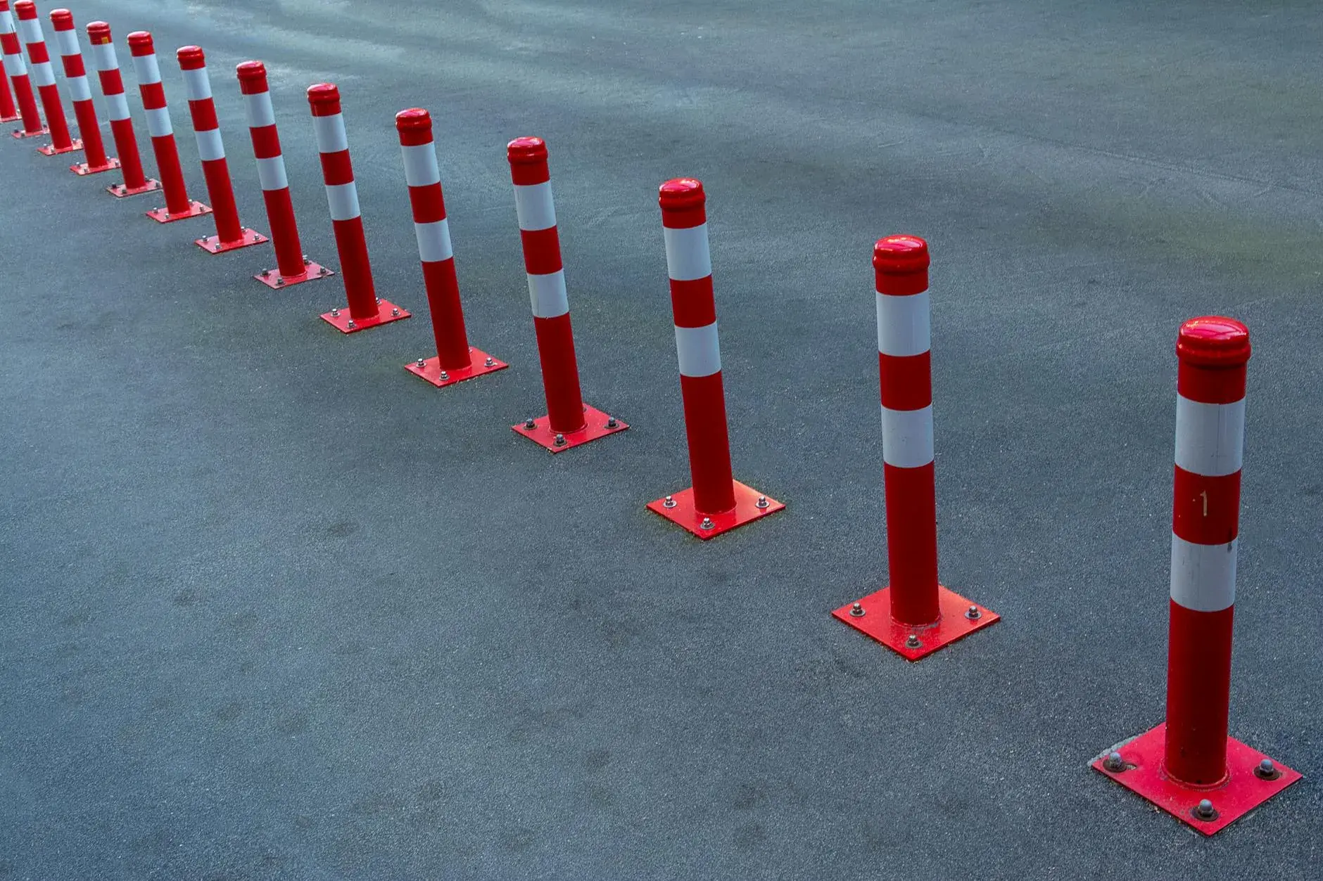 En linje af røde og hvide kantpæle står langs asfalten og markerer et område til trafikregulering. Billedet understreger sikkerhed og orden i vejmiljøet.