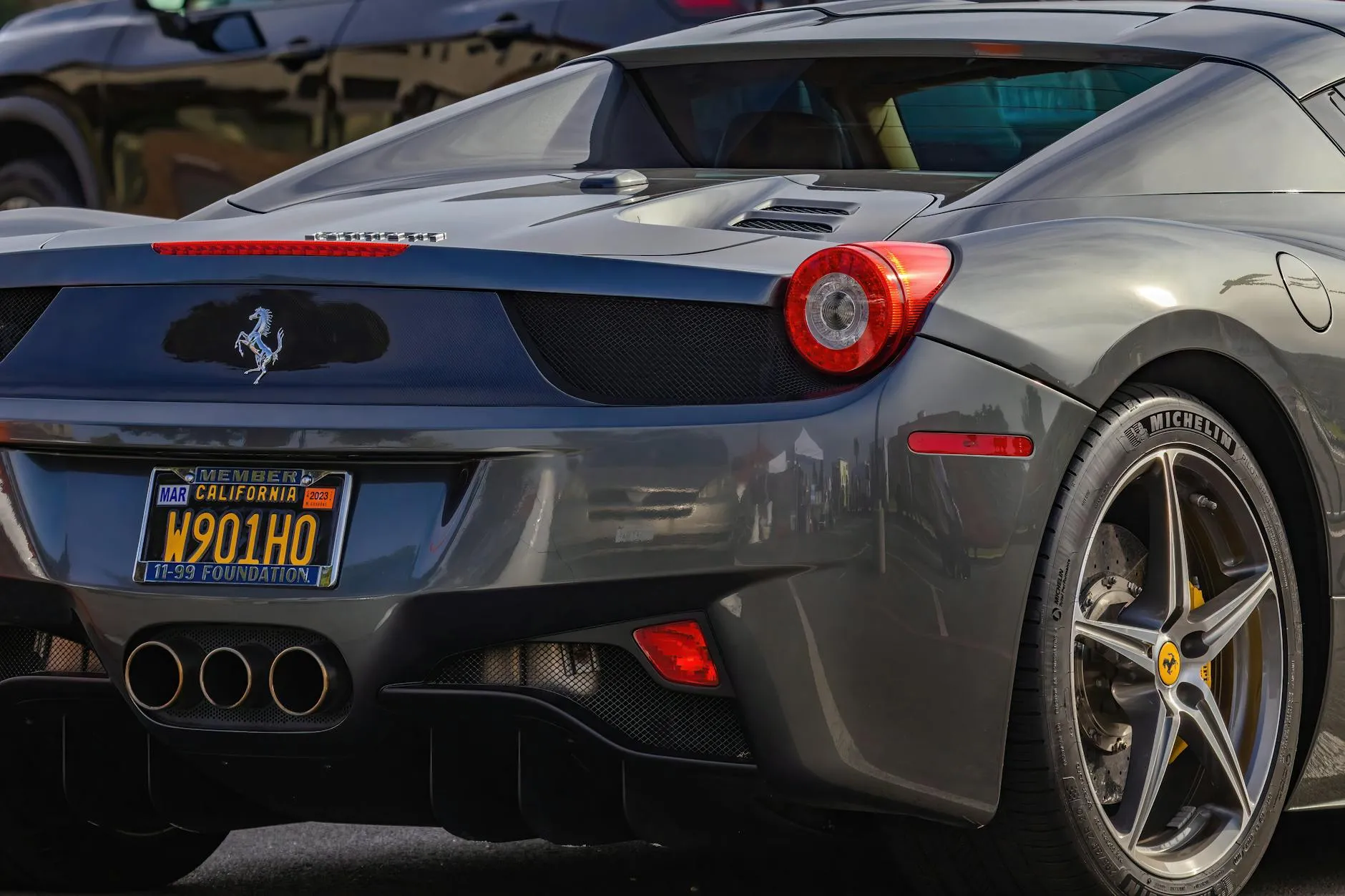 Et tæt nærbillede af en elegant grå Ferrari, der fremhæver bilens luksuriøse design og ikoniske emblem. Fokus er på bilens detaljer og overflader.