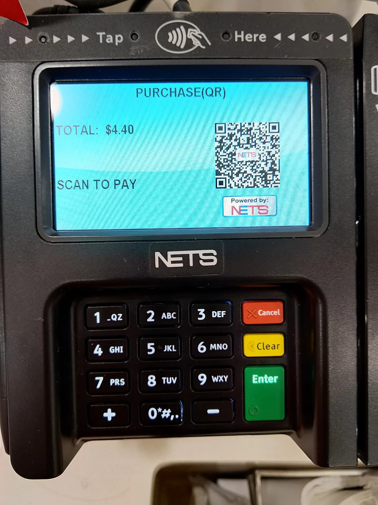 En Ingenico ISC250 betalingsterminal behandler en transaktion via en dynamisk NETS QR-kode. Billedet viser terminalens skærm og QR-betalingsflow.