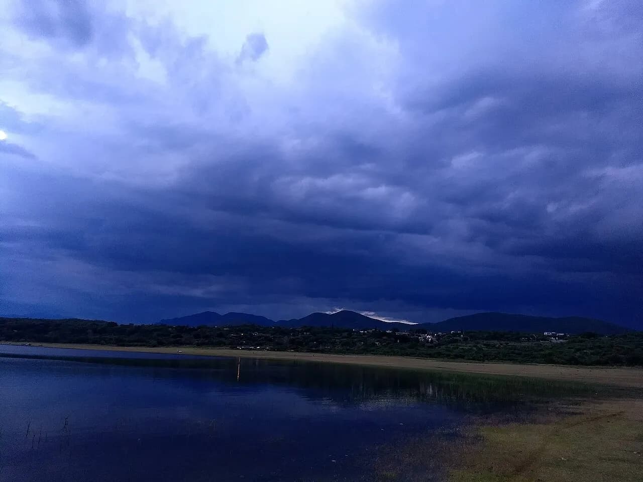 Fotografi af lagunen El Rodeo ved solnedgang i Miacatlán. Stemningen er præget af det varme aftenlys over vandet.