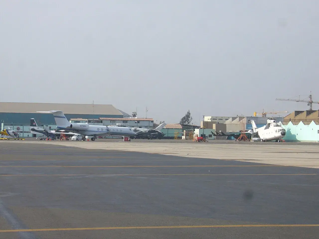 En samling militærfly, herunder Mi-26, Mi-8 og An-32, parkeret ved Jorge Chávez Internationale Lufthavn. Billedet viser militær luftfart i lufthavnsområdet.