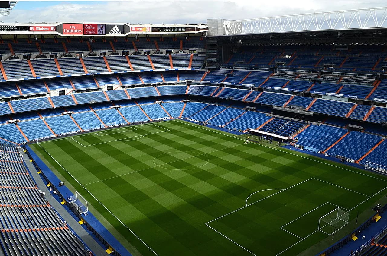 Et bredt panoramabillede af Santiago Bernabéu Stadion i Madrid. Perspektivet viser stadionets samlede form og den markante placering i byens sportslandskab.