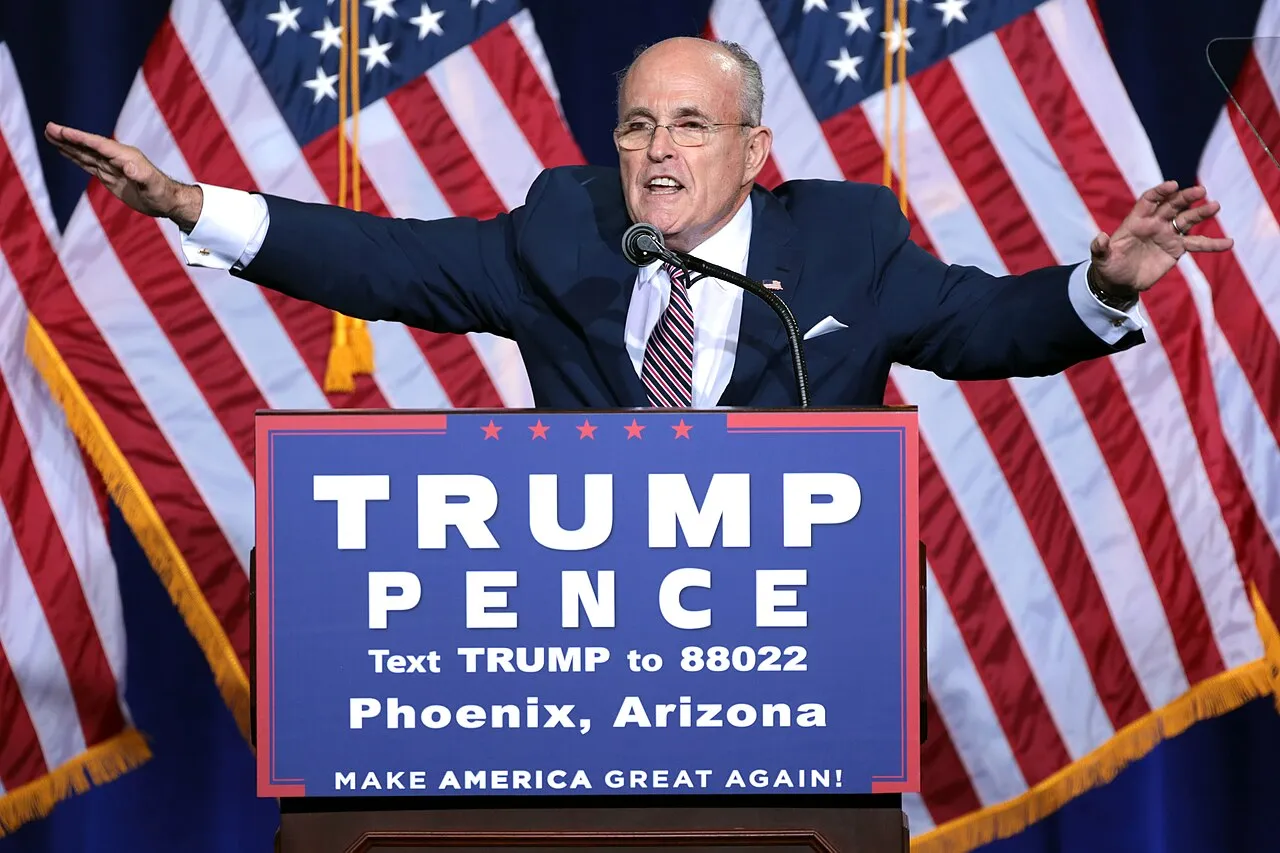 Rudy Giuliani taler ved en immigration policy-speech i Phoenix, Arizona, hostet af Donald Trump. Billedet viser ham i fokus under et politisk arrangement.