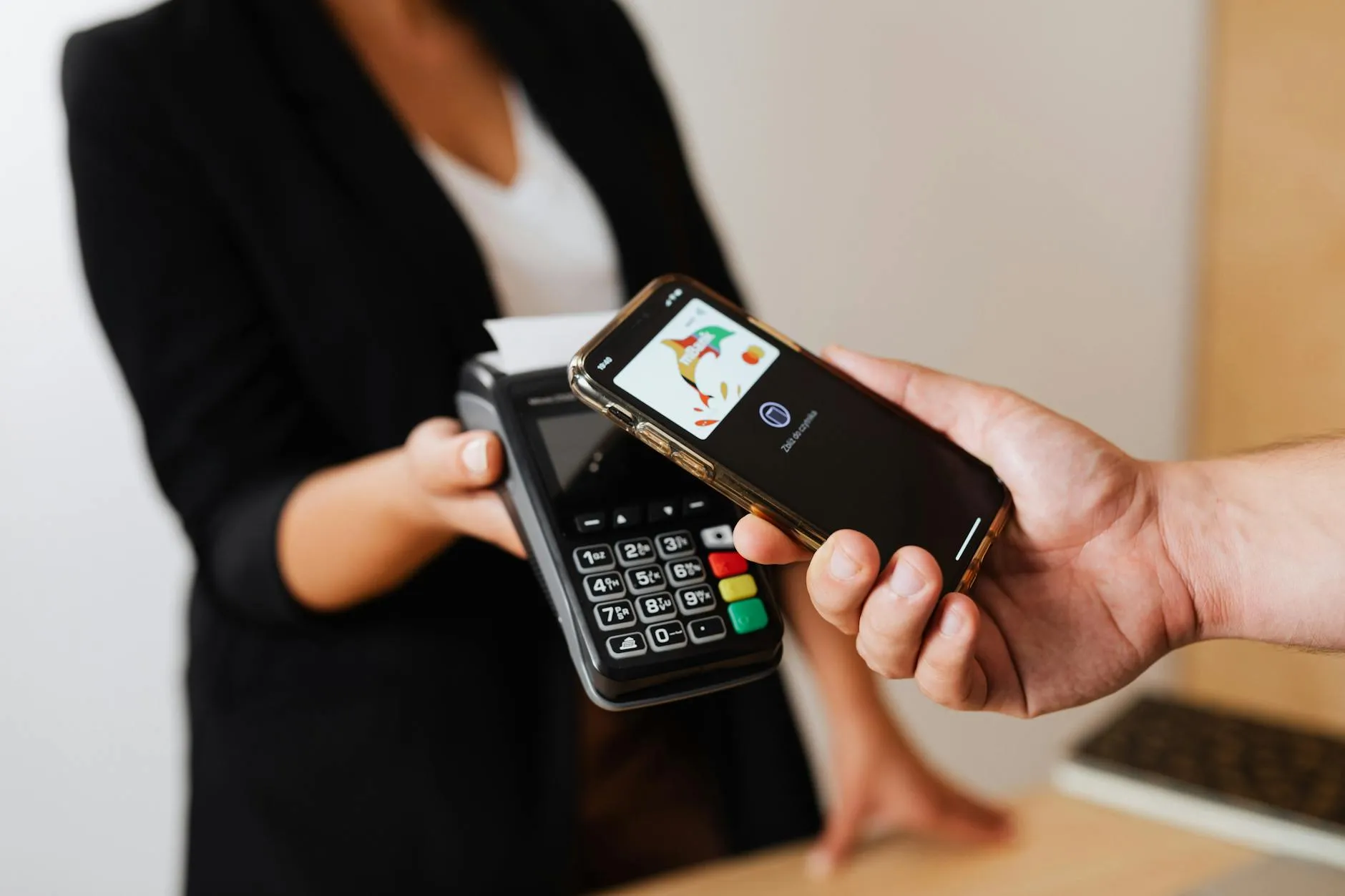 En person gennemfører en kontaktløs betaling med en smartphone ved en butikskasse. Billedet illustrerer hurtige og sikre betalinger i hverdagen.