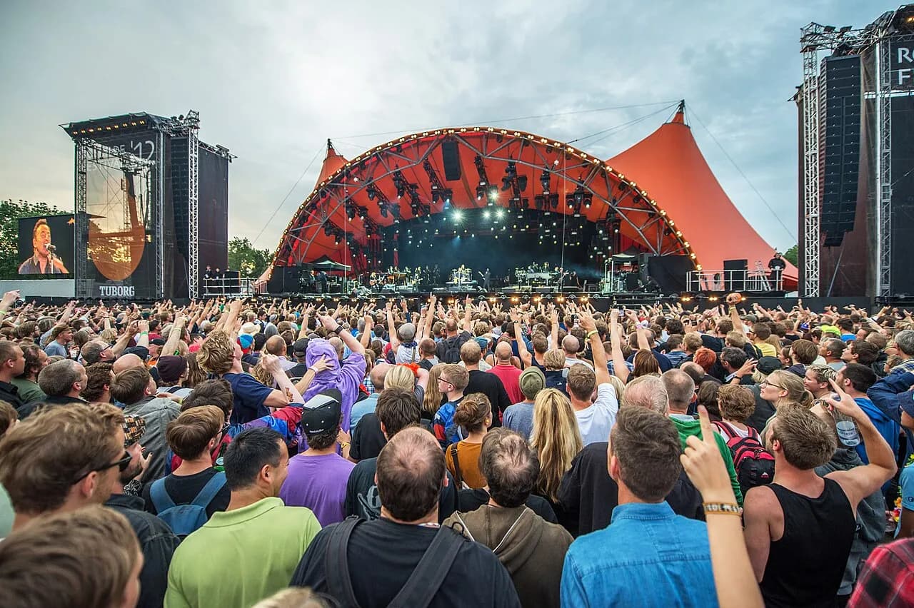Billedet viser Roskilde Festivals hovedscene, Orange Stage, med Bruce Springsteen optrædende i baggrunden. Et ikonisk øjeblik fra festivalen.