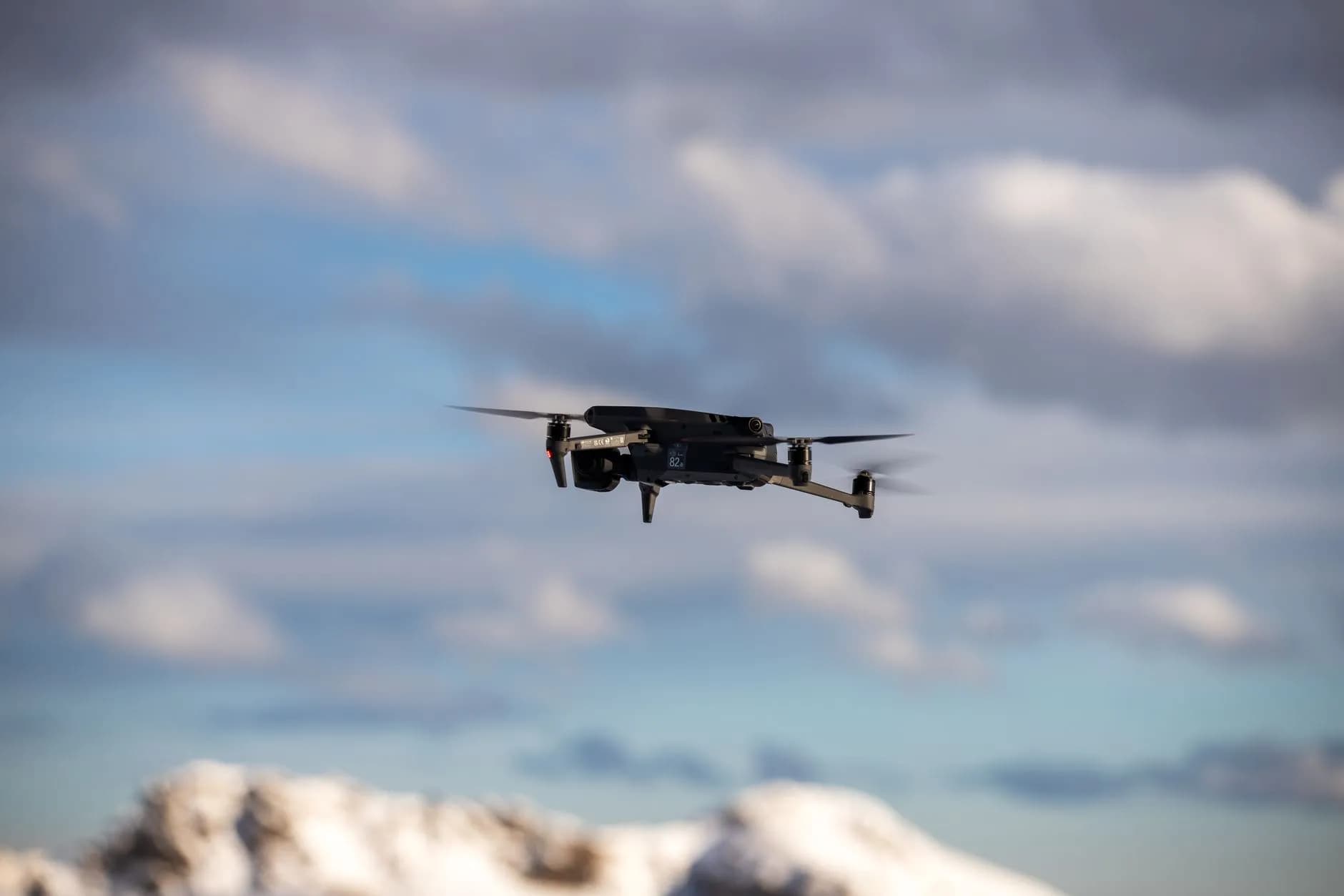 Et fly ses på himlen mod en skyet baggrund, fanget i et dynamisk perspektiv. Billedet understreger bevægelse og luftfartens atmosfære.