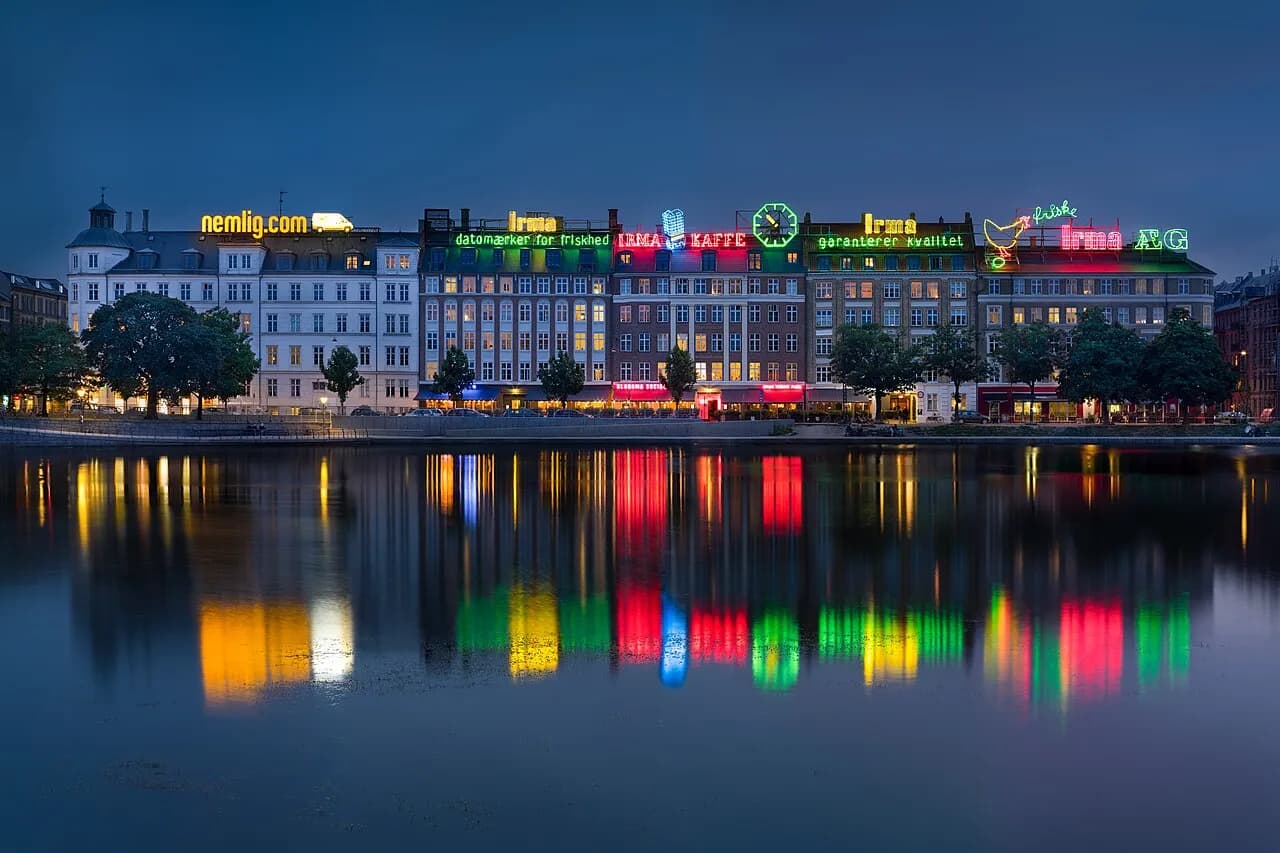 Udsigt over Københavns skyline med de ikoniske neonreklamer over søerne. I billedet ses Irma Block (Irma Karréen) på Sortedam Dossering, hvor Irmahønen er Danmarks ældste neonskilt.