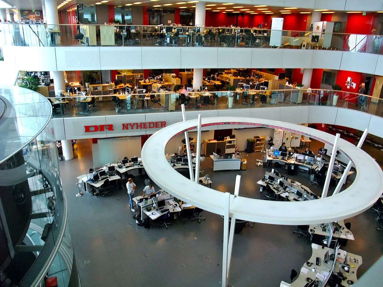 Et nyhedslokale hos Danmarks Radio, hvor journalister arbejder med produktion til web, TV og radio. Billedet viser stemningen i et moderne redaktionsmiljø.