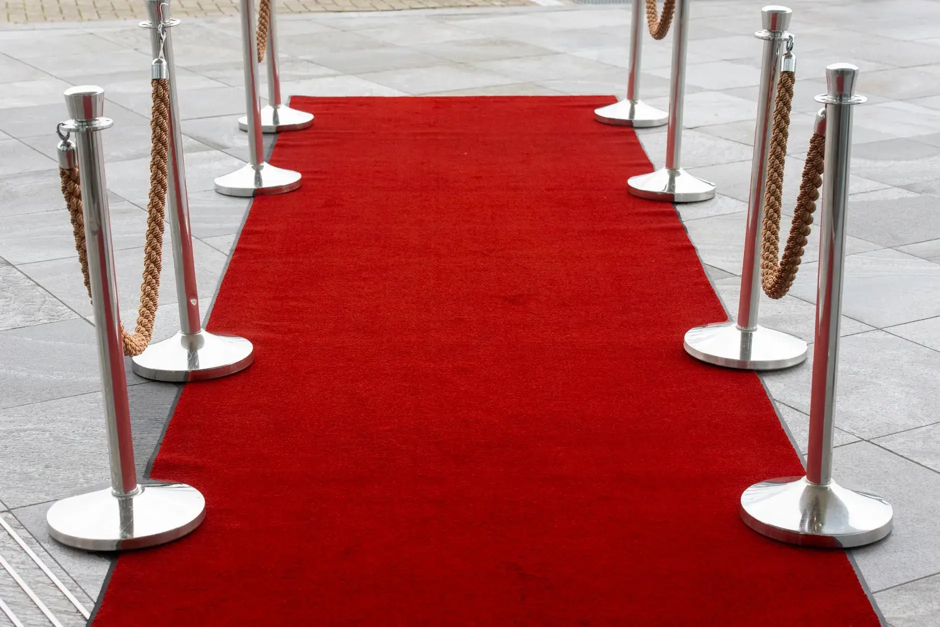 En rød løber med stanchions på en fliset udendørs overflade, perfekt til events.