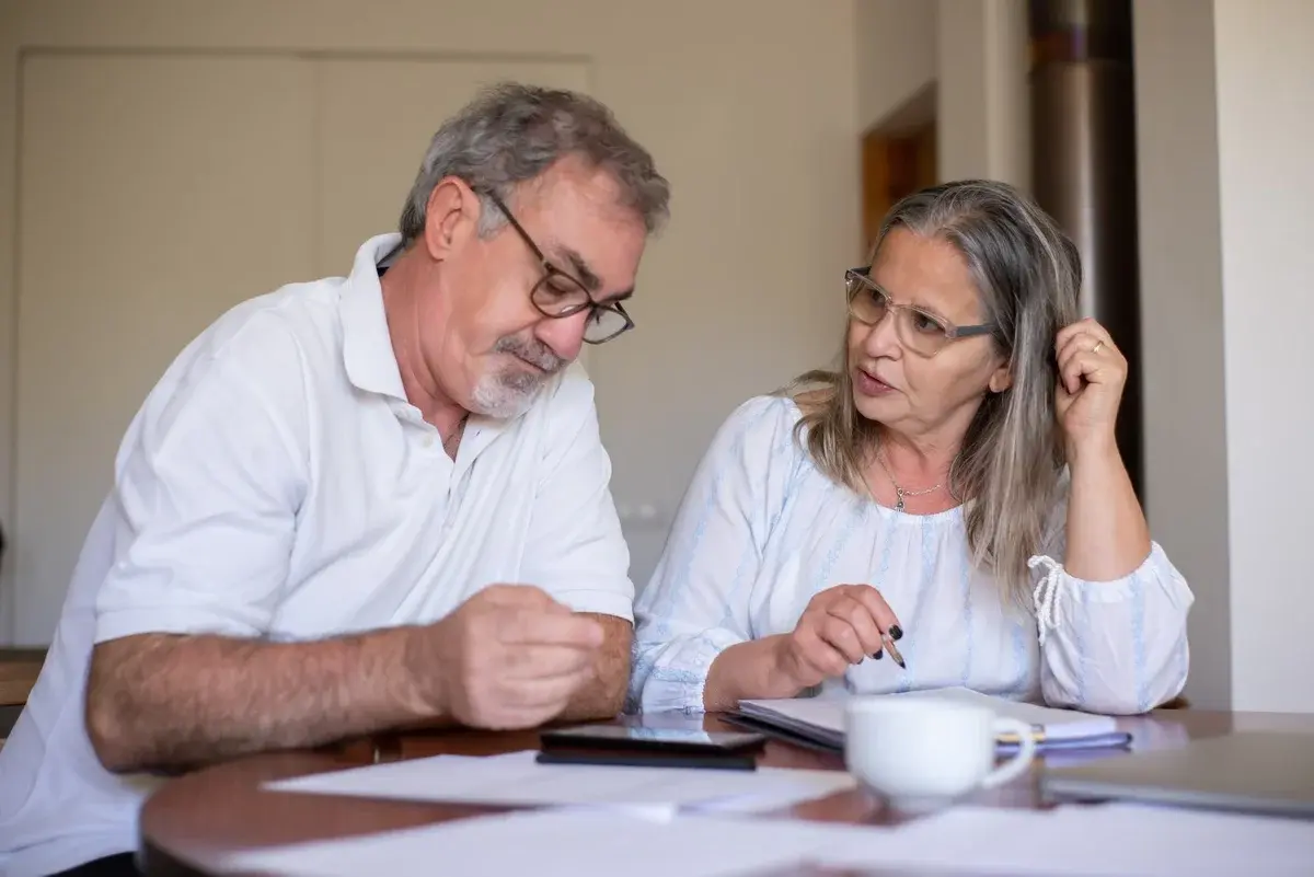A senior couple reviews paperwork together at a table.
