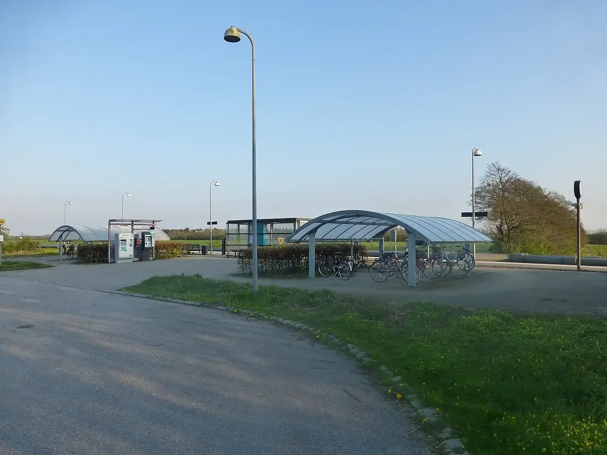 A quiet Danish railway station platform with bicycle shelters and lamps.