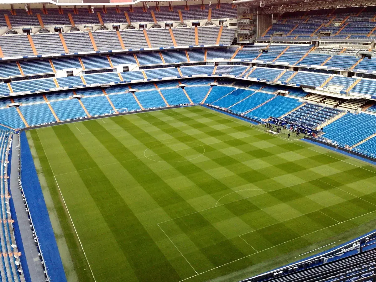 Empty soccer stadium with green field and blue seats