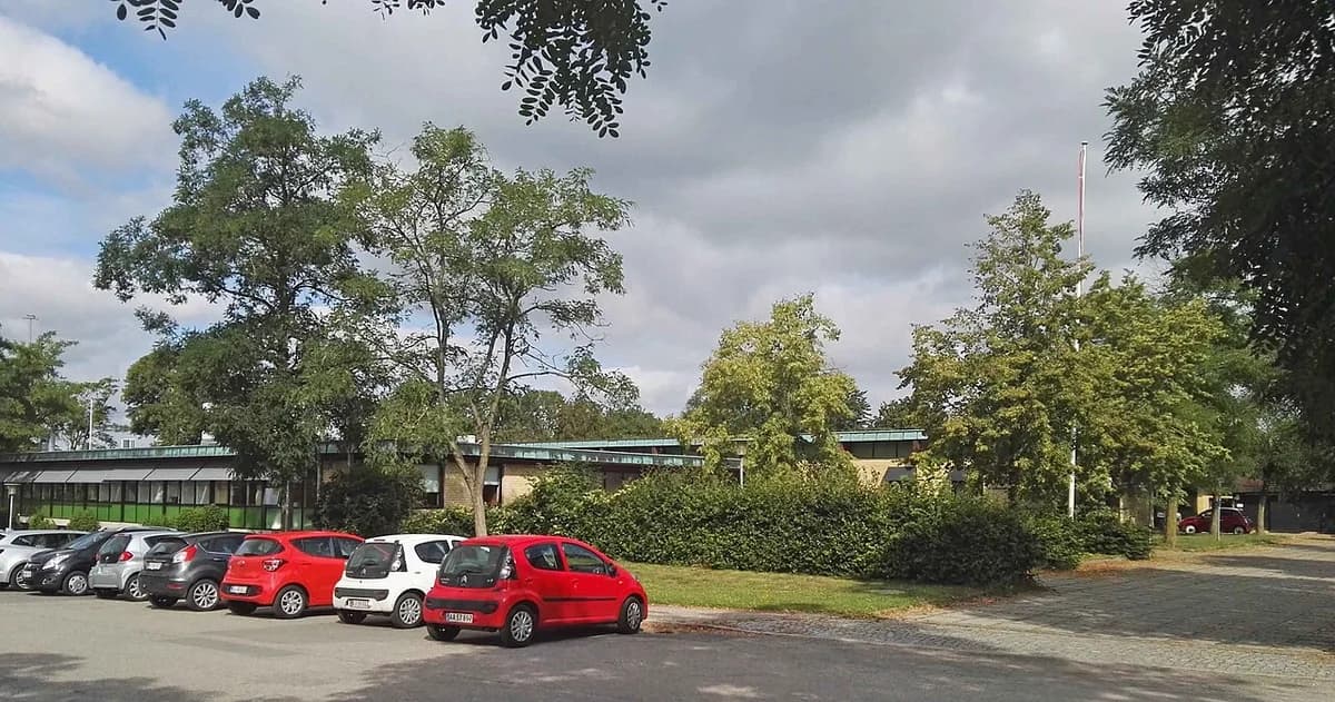 Exterior of the former town hall in Tølløse with parked cars and trees.