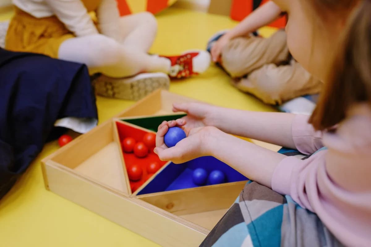 Children playing with colorful balls in wooden box