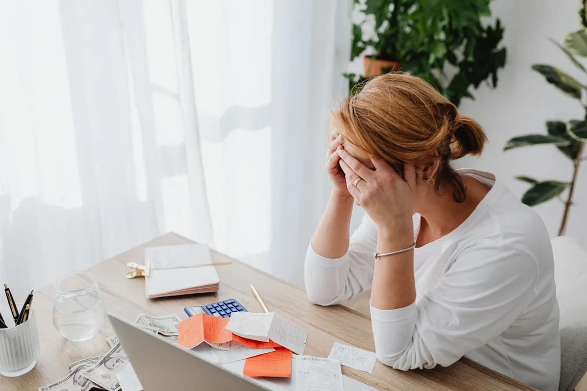 Woman stressed at desk with financial receipts