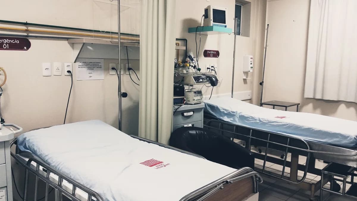 An empty hospital room with two beds and medical equipment.