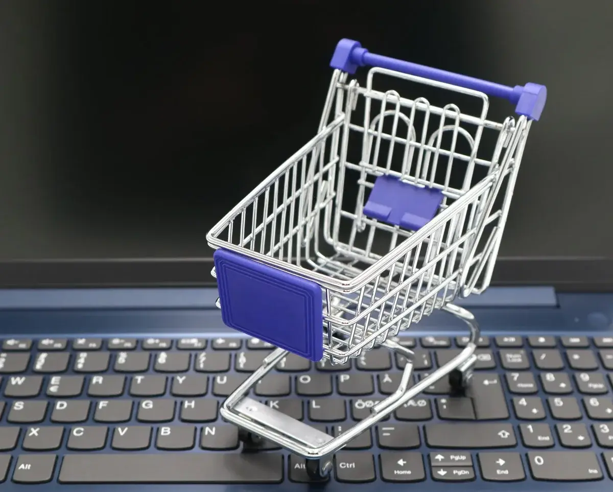 A miniature shopping cart sitting on a laptop keyboard.