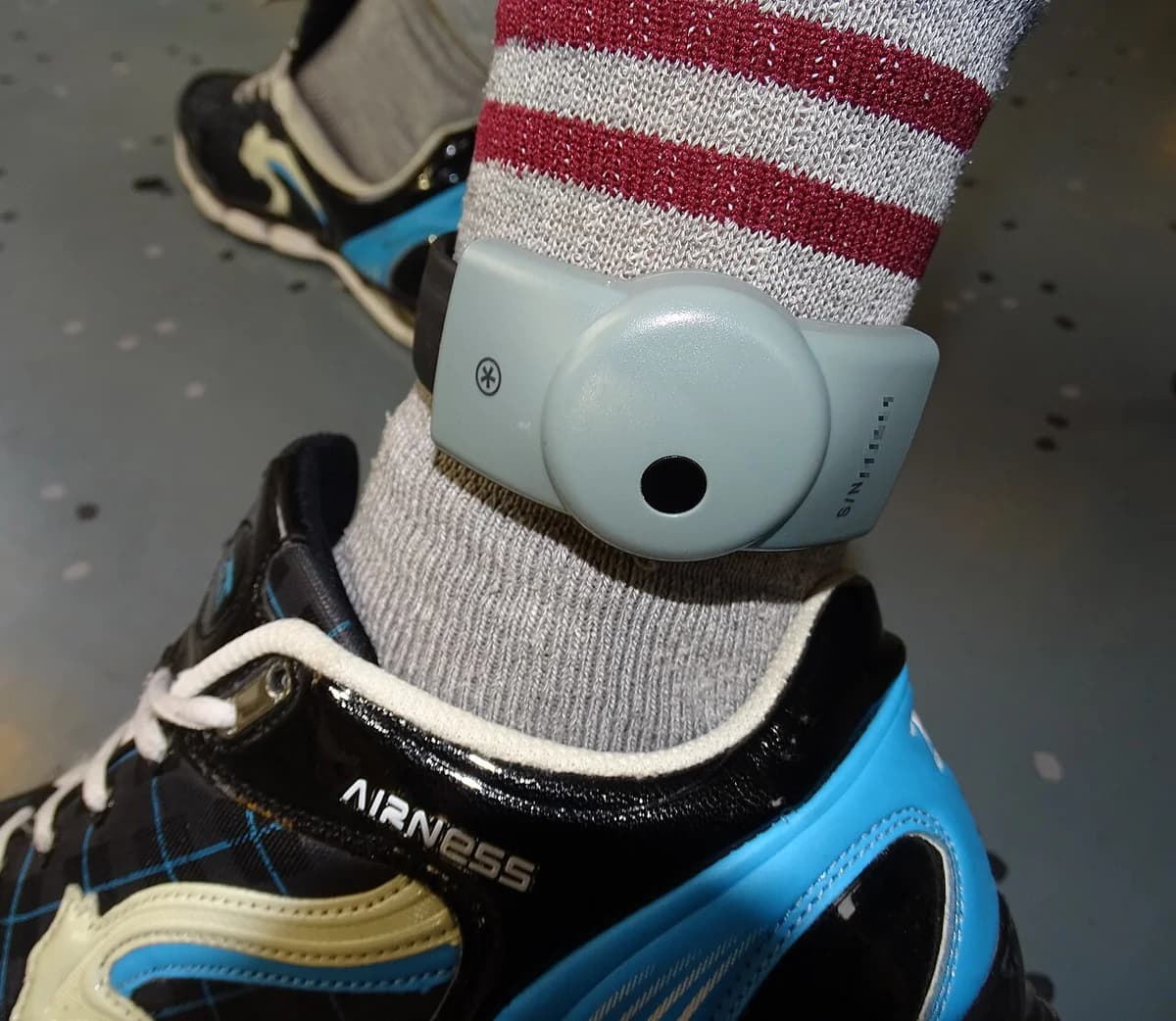 Electronic ankle monitor strapped above sock and sneaker