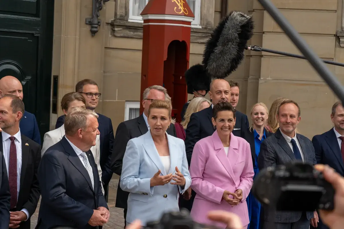 Danish politicians standing together during a government presentation at Amalienborg Palace Square.