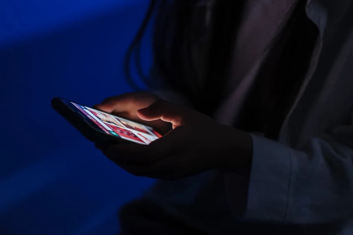 Teenager looking at a smartphone in a dark room.