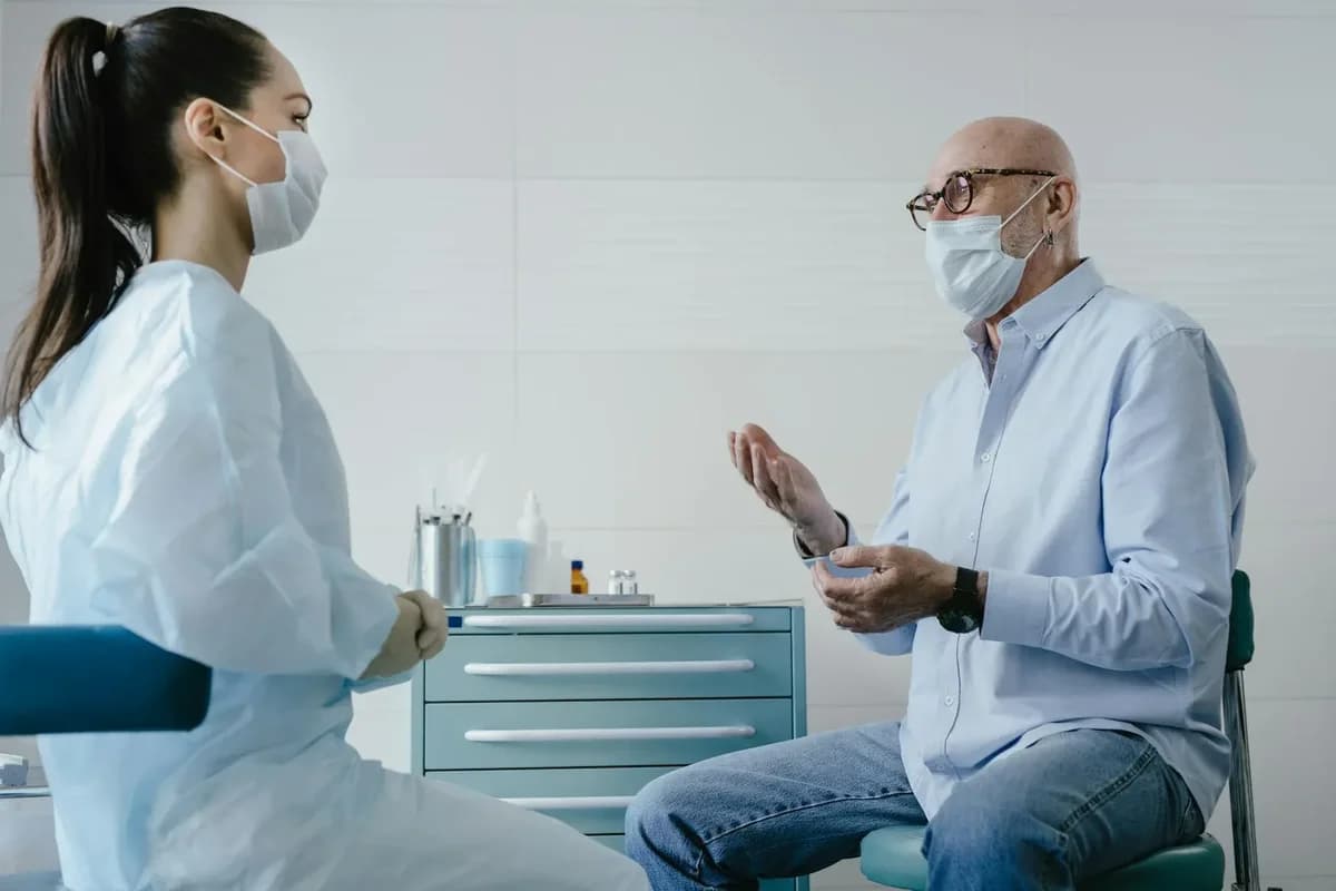 Elderly patient talking to masked doctor in clinic