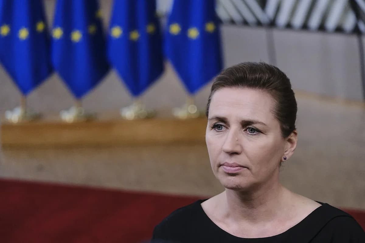 Portrait of Danish Prime Minister Mette Frederiksen in front of EU flags.