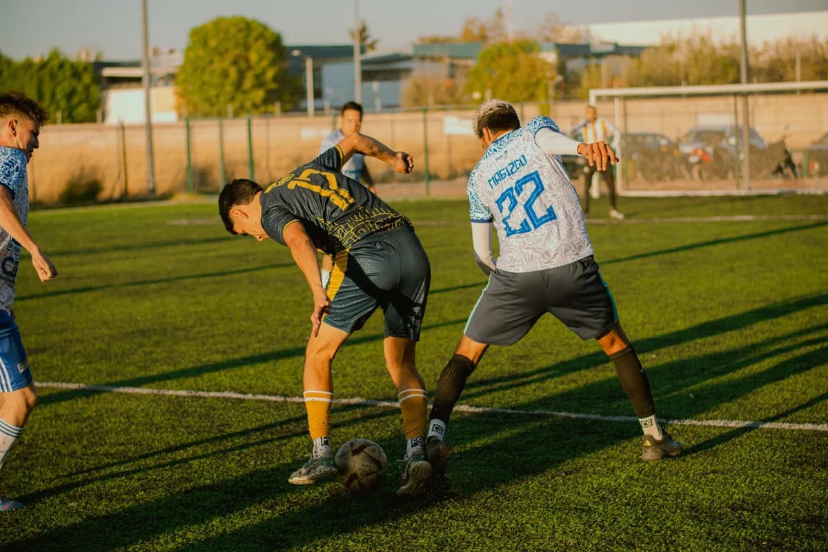 Soccer players competing for the ball on a sunny field.