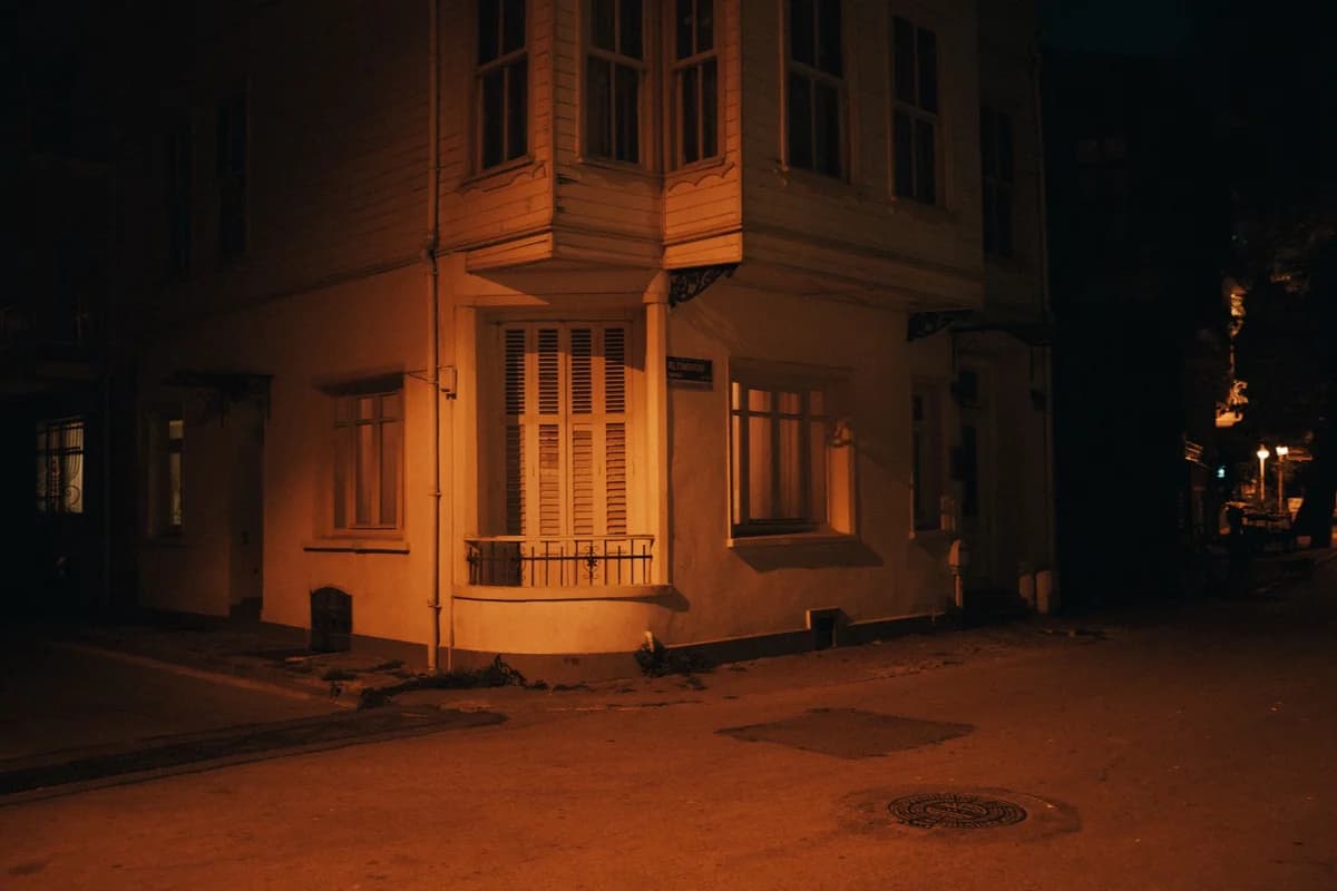 A warmly lit apartment building corner at night on a quiet street.