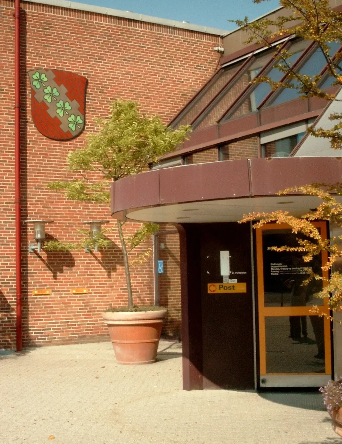 Entrance to Høje-Taastrup Town Hall with a municipal coat of arms on the brick wall.