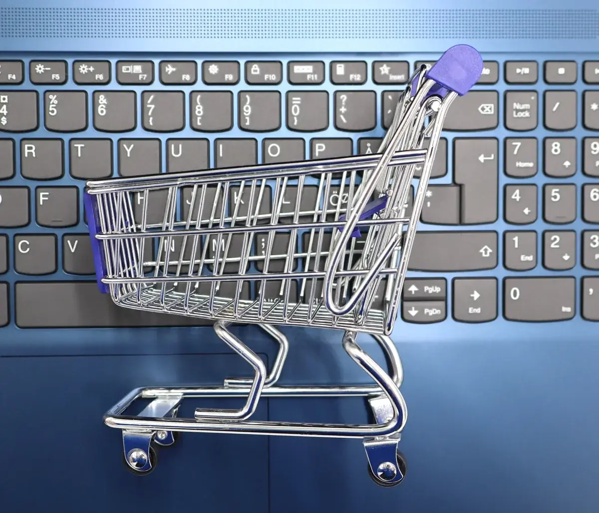 A miniature shopping cart sitting on a laptop keyboard.