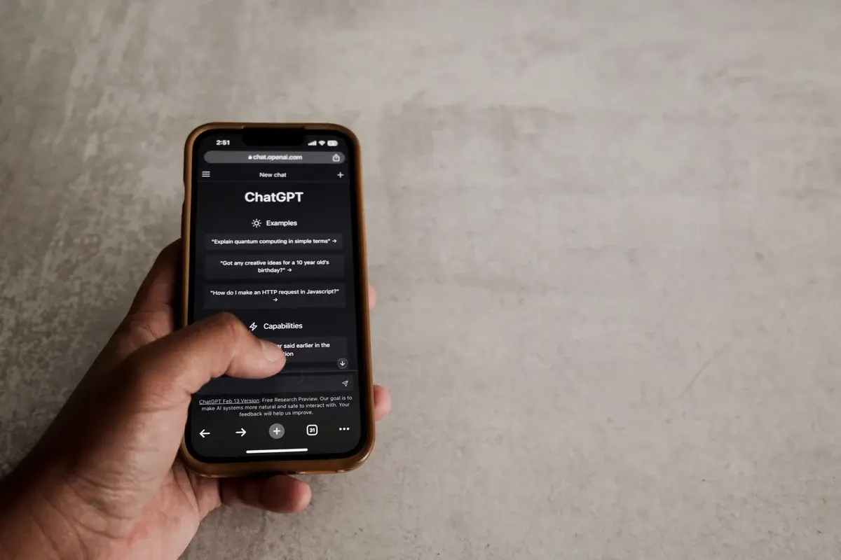 A hand holding a smartphone displaying ChatGPT.