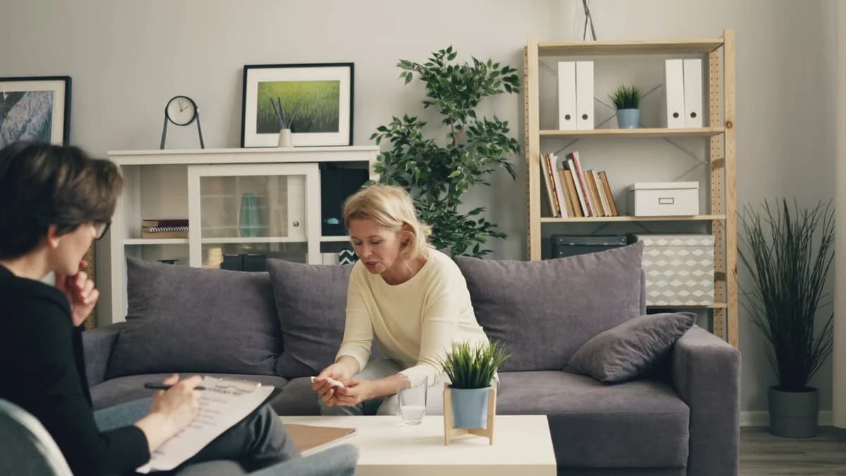A woman speaking with a therapist in a cozy living room.