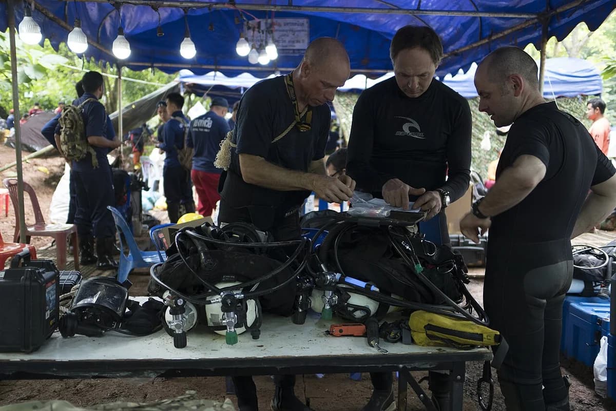 Rescue divers preparing scuba gear at a cave site in Thailand.