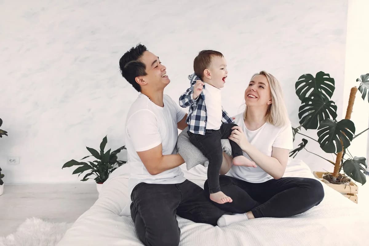 A smiling family with a young child sitting together indoors.