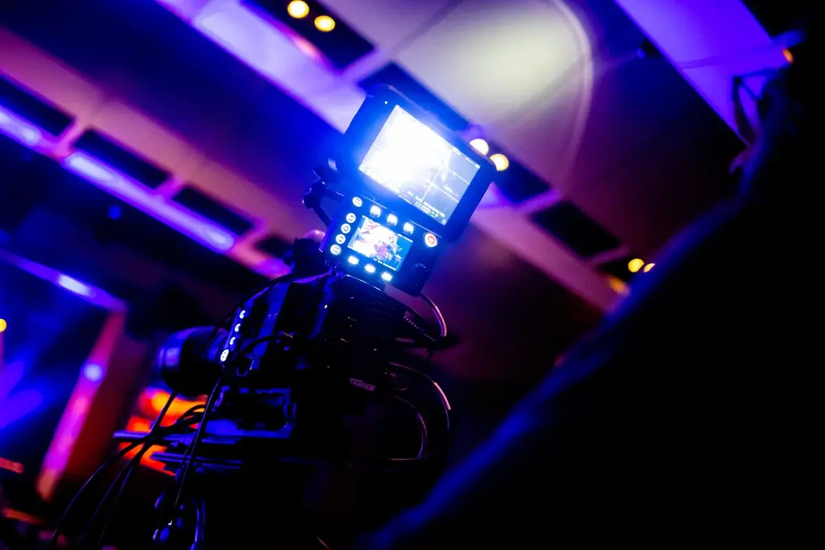 Close-up of a video camera under colorful studio lights.
