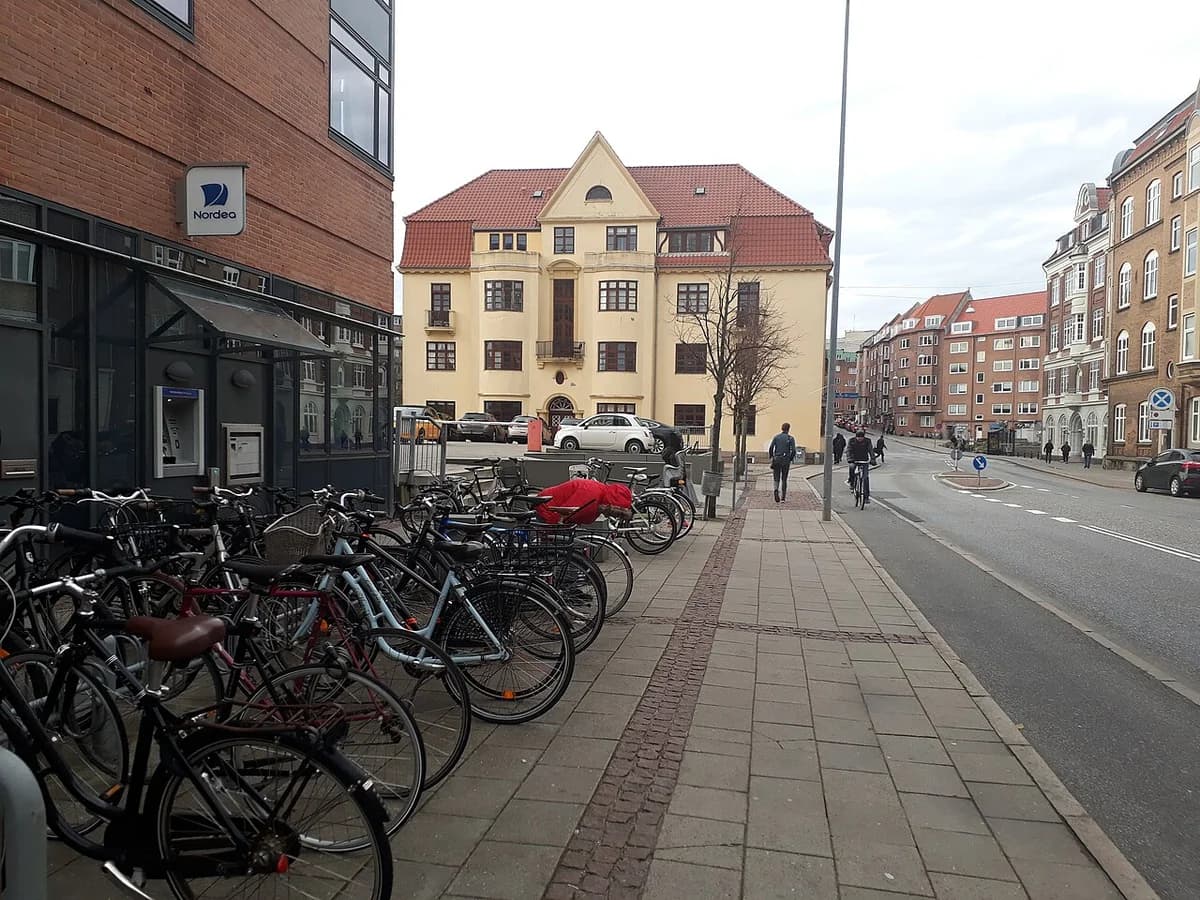 Street scene with many parked bicycles beside a Nordea ATM and surrounding urban buildings.