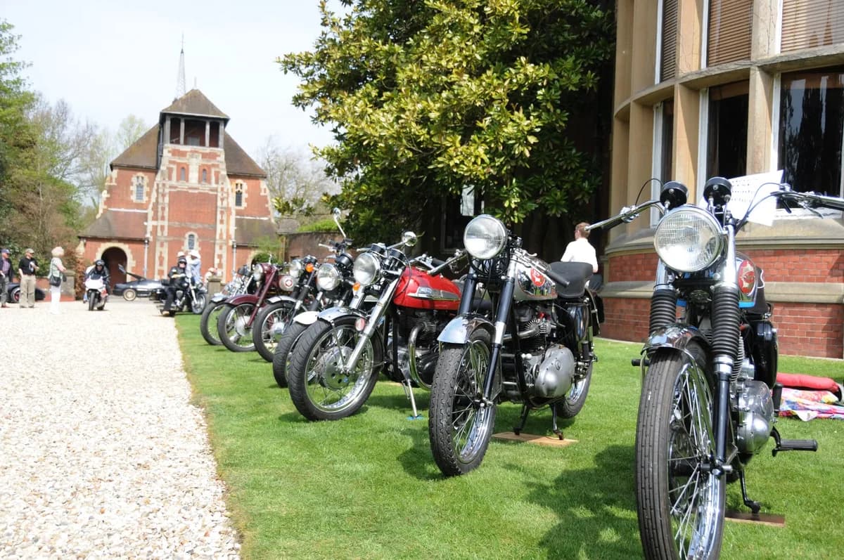 Row of vintage motorcycles lined up outdoors on grass
