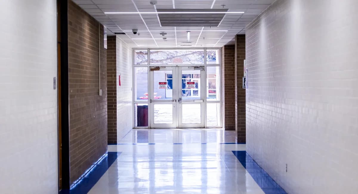 Bright school hallway with glass exit doors and 'Do Not Enter' signs
