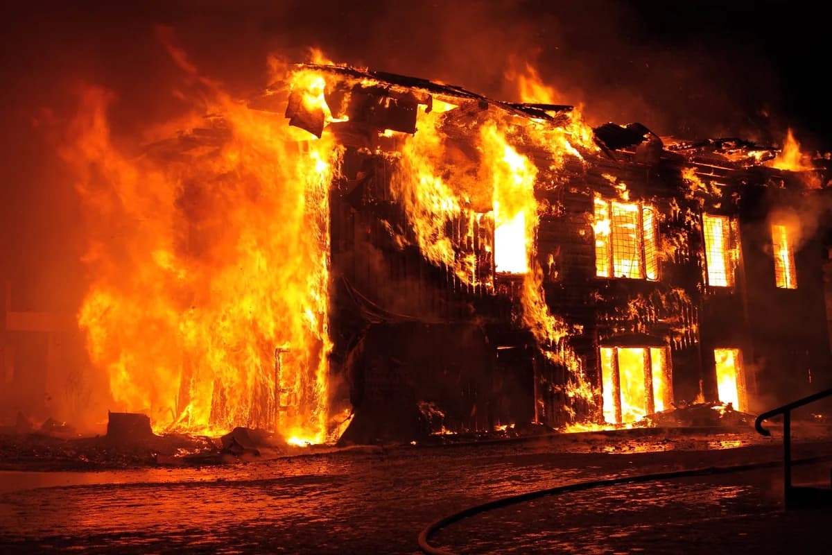 A house burning intensely at night.