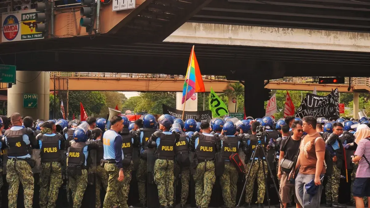 Line of police officers and protesters under a bridge