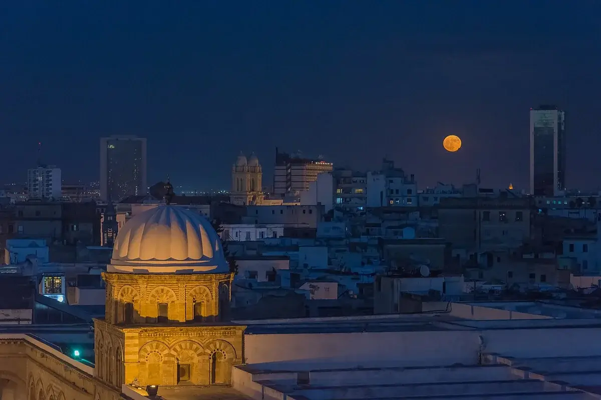 Night view of Tunis with a supermoon over the city skyline.