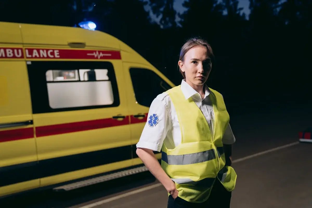 Female paramedic standing beside an ambulance at night