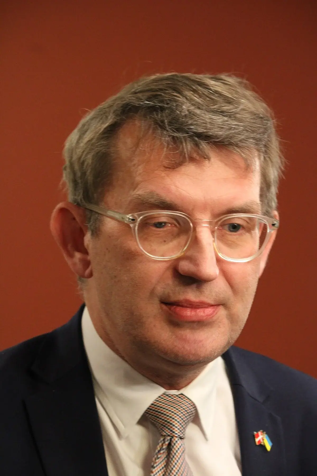 Close-up portrait of a man in glasses and a suit.